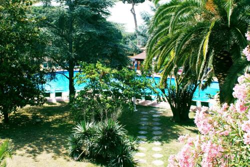 un complejo con piscina y palmeras en DEPENDANCE PARCO dei PRINCIPI, en Anzio