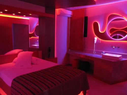 een slaapkamer met roze lampjes en een bed en een wastafel bij Uman Hotel -Motel- in Buenos Aires