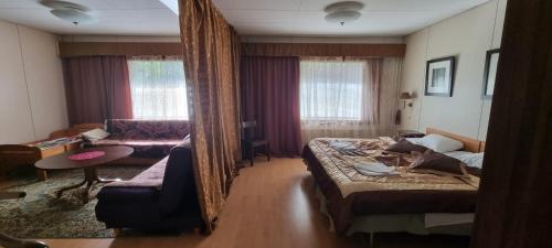 a bedroom with a bed and a couch and a mirror at Hotel Villa Vanessa in Siltakylä