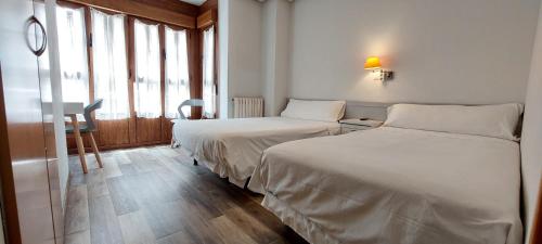 um quarto de hotel com duas camas e uma janela em Pensión Romero em Oviedo