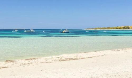 a beach with some boats in the water at Appartamento Capo Mannu-mandriola in Putzu Idu