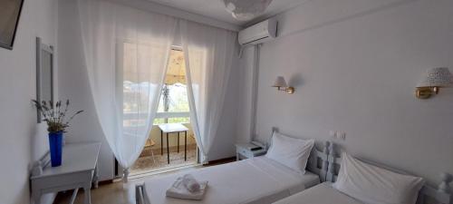 a white room with a bed and a window at Hotel Rania in Loutra Edipsou