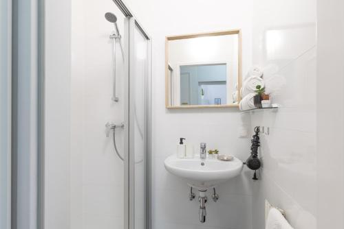biała łazienka z umywalką i lustrem w obiekcie Yeshello Vienna Central Station Apartment w Wiedniu