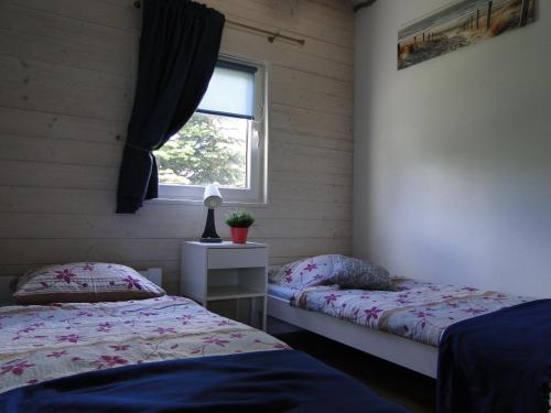a bedroom with two beds and a window at Domki Zielona Osada in Szczenurze