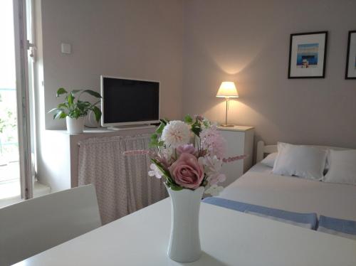 a white vase with flowers on a table in a bedroom at Apartment Bella Vista in Belgrade