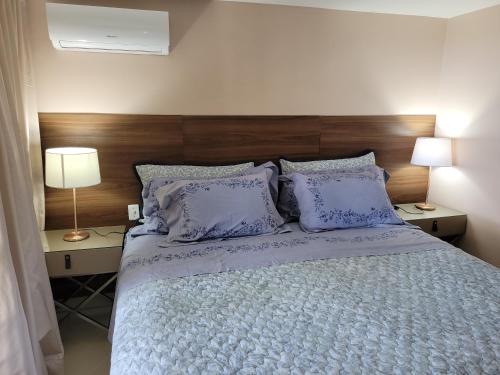 a bedroom with a bed with pillows and two lamps at Solar dos Arcos in Praia do Forte