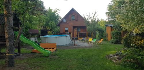 a yard with a playground with a slide and a house at Szyszka i Róża Domek na Jurze in Zelasko