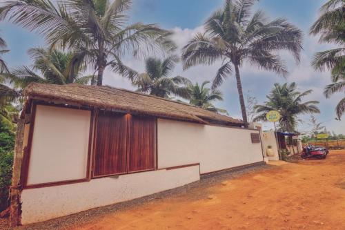 a small building with palm trees in the background at Pause By The Sea in Morjim