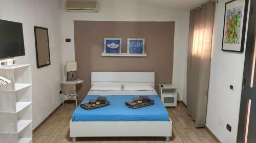 a bedroom with a bed with blue sheets and shoes on it at Casa Peloritani in Siracusa