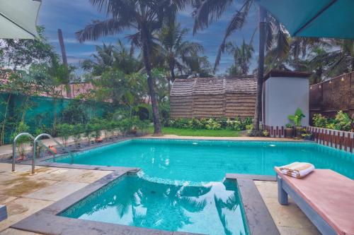 a swimming pool with a bench in front of a house at Pause By The Sea in Morjim