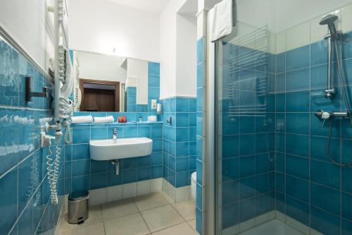 y baño de azulejos azules con lavabo y ducha. en Hotel Słoneczny Młyn, en Bydgoszcz