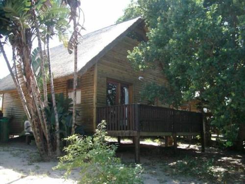 a small wooden house with a porch and trees at Sodwana Bay Lodge Dive & Fishing Resort in Sodwana Bay