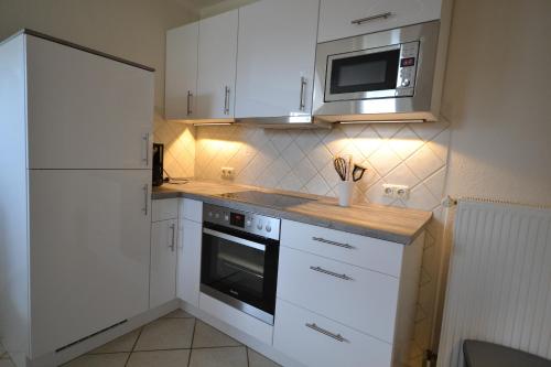 a kitchen with white cabinets and a microwave at Haus Sir Henry in Grömitz
