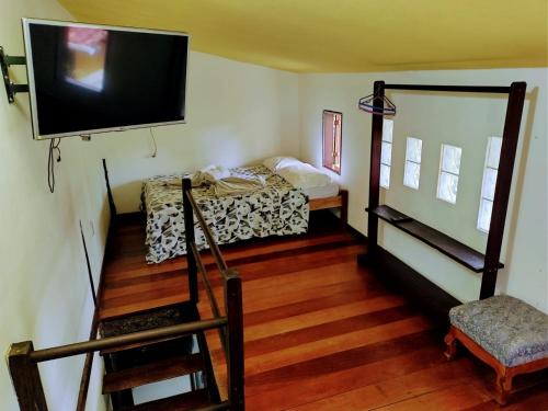 um quarto com uma cama e uma televisão na parede em Canto das Orquídeas em Paraty