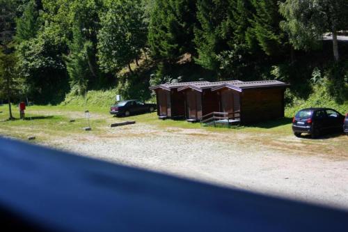 a small cabin with cars parked in a field at Camping Yoghi e Bubu in San Giacomo