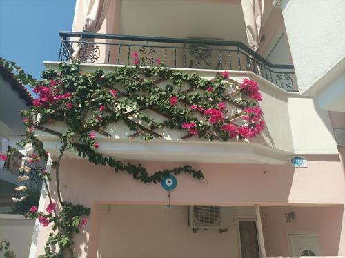 un balcón con flores rosas en un edificio en Filomeni Studios, en Pefkohori