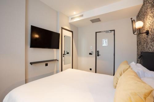 a bedroom with a white bed and a flat screen tv at Hôtel Prince Albert Gare de Lyon in Paris