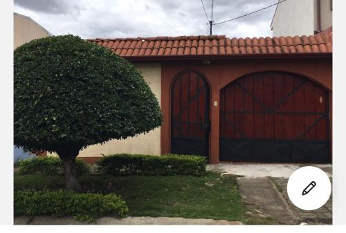 a house with two garage doors and a tree at Room near Airport/ Cerca del Aeropuerto in Santiago Este
