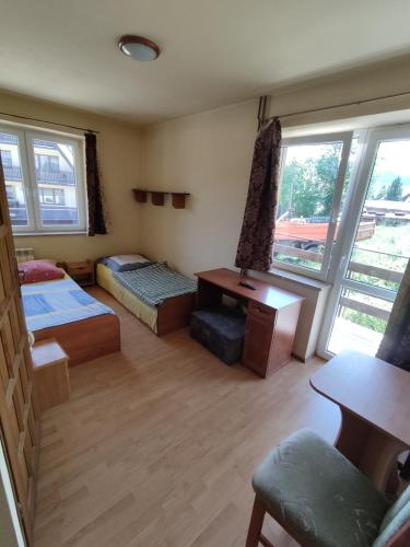 a room with two beds and a desk and windows at Pokoje na Sobczakówce in Zakopane