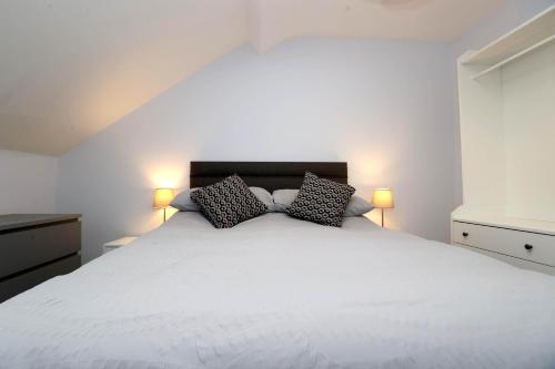 a bedroom with a large white bed with two pillows at Entire penthouse apartment with sea views Portrush in Portrush