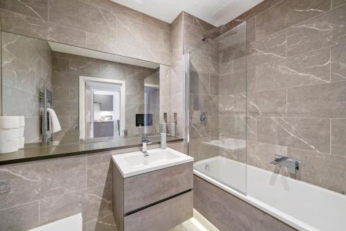 a bathroom with a tub and a sink and a bath tubermott at Stunning, New & Stylish 1 Bed Apartment in Ramsgate