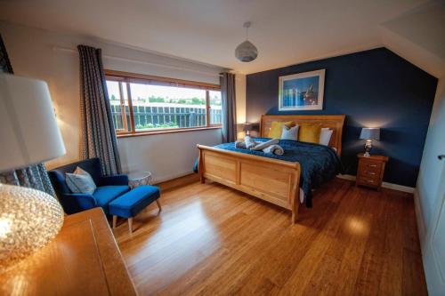 - une chambre avec un lit et un mur bleu dans l'établissement Mourne Magic House-Riverside luxury in Newcastle, à Newcastle