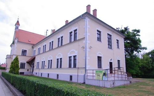 ein großes weißes Gebäude mit einer Hecke davor in der Unterkunft Koleje Zamecek in Lednice