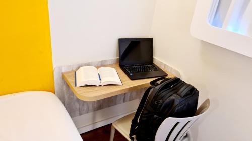 a laptop computer sitting on a desk with a book at ibis budget Petropolis in Petrópolis