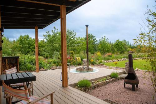 a wooden deck with a fountain in a garden at Peaceful Bothy Retreat in Nairn
