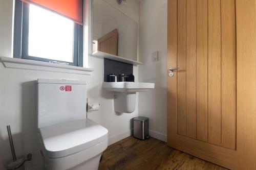 a bathroom with a toilet and a sink and a window at Peaceful Bothy Retreat in Nairn