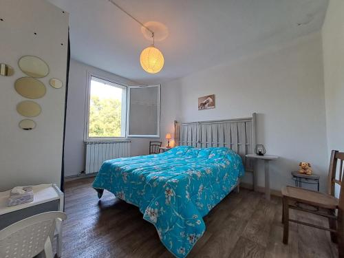 1 dormitorio con 1 cama con edredón azul y ventana en Les Reflets du Tarn, en Ambialet