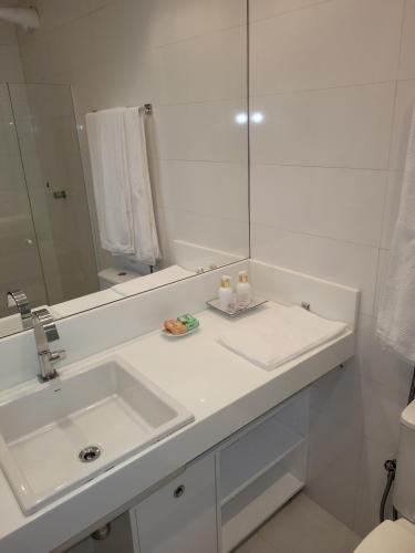 a white bathroom with a sink and a mirror at Solar dos Arcos in Praia do Forte