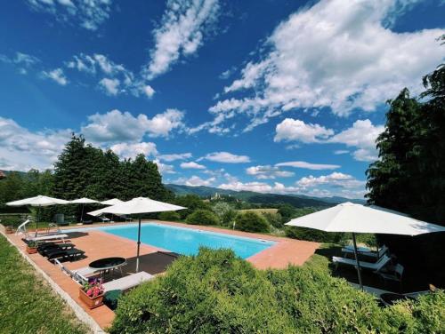 a swimming pool with umbrellas and chairs at Borgo Romena in Pratovecchio
