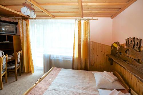a bedroom with a bed with a wooden headboard and a window at Smerekovyi Dvir in Zhdenievo