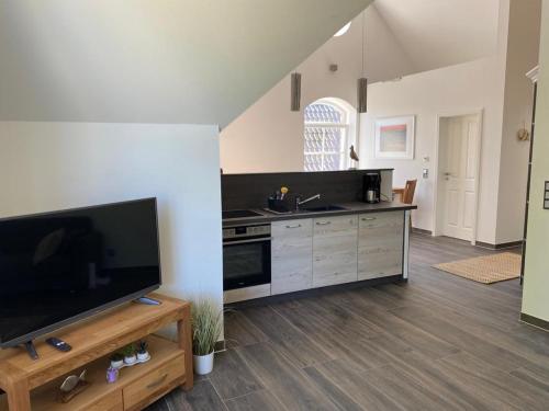 a living room with a large television and a kitchen at Haus Sophie in Zingst