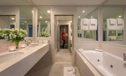 - une grande salle de bains blanche avec deux lavabos et une baignoire dans l'établissement Castletroy Park Hotel, à Limerick