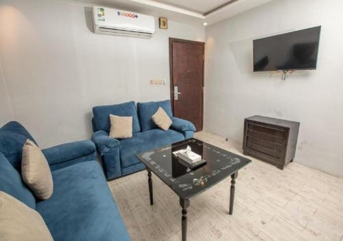 a living room with a blue couch and a table at ميرا سويت للشقق المخدومة in Jeddah