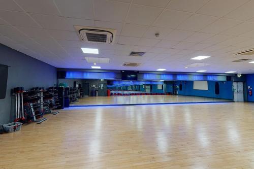 an empty gymnasium with a wooden floor and blue walls at Village Hotel Liverpool in Prescot