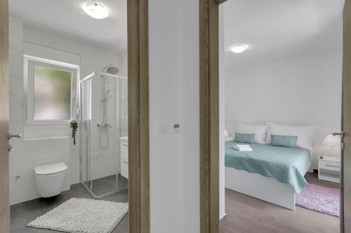 a white bedroom with a bed and a bathroom at Central Makarska - Apartments Šantrić in Makarska