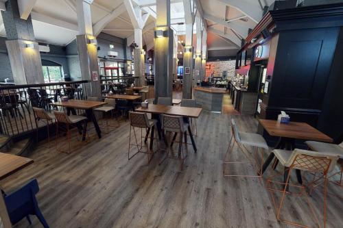 an empty restaurant with wooden tables and chairs at Village Hotel Liverpool in Prescot