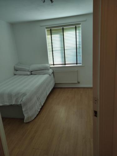a white bedroom with a bed and a window at Immaculate 1-Bed Apartment in Borehamwood in Borehamwood