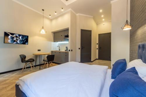 a bedroom with a large white bed and a kitchen at Secret Apartments in Kyiv