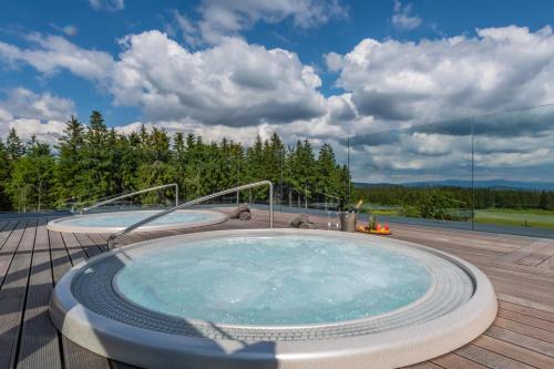 a hot tub on the deck of a house at Hotel Královka in Bedřichov