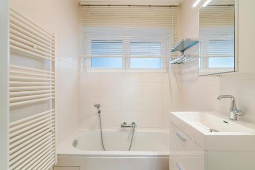 Un baño blanco con bañera y lavabo. en Modern, mooi en stijlvol app vlakbij winkelstraat, en Knokke-Heist