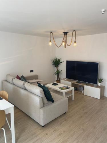 a living room with a couch and a flat screen tv at Las Terrazas de Güeli 6 pax WiFi - GARAJE - Vistas - VUT-3391-AS in Gijón