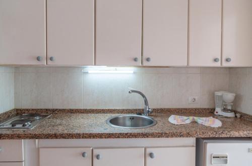 a kitchen counter with a sink and white cabinets at Apartamentos Chinyero in Puerto de la Cruz