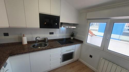 a kitchen with white cabinets and a sink and a window at Las Terrazas de Güeli 6 pax WiFi - GARAJE - Vistas - VUT-3391-AS in Gijón