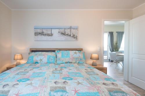 a bedroom with a bed with a colorful bedspread at Penthouse SeeZeichen mit Seeblick in Nordstrand