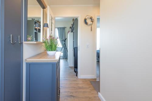 a hallway with blue cabinets and a blue kitchen at Penthouse SeeZeichen mit Seeblick in Nordstrand
