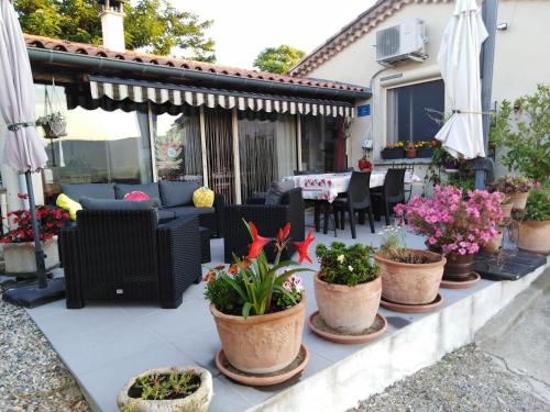 un patio con macetas, mesa y sillas en LA GRAND'VIGNE, en Chauzon